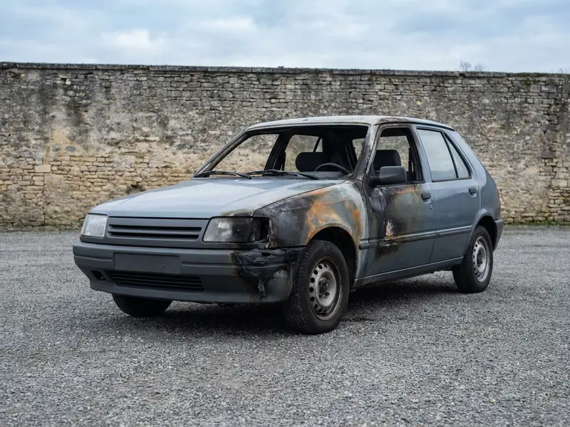 Voiture partiellement brûlée sur un terrain